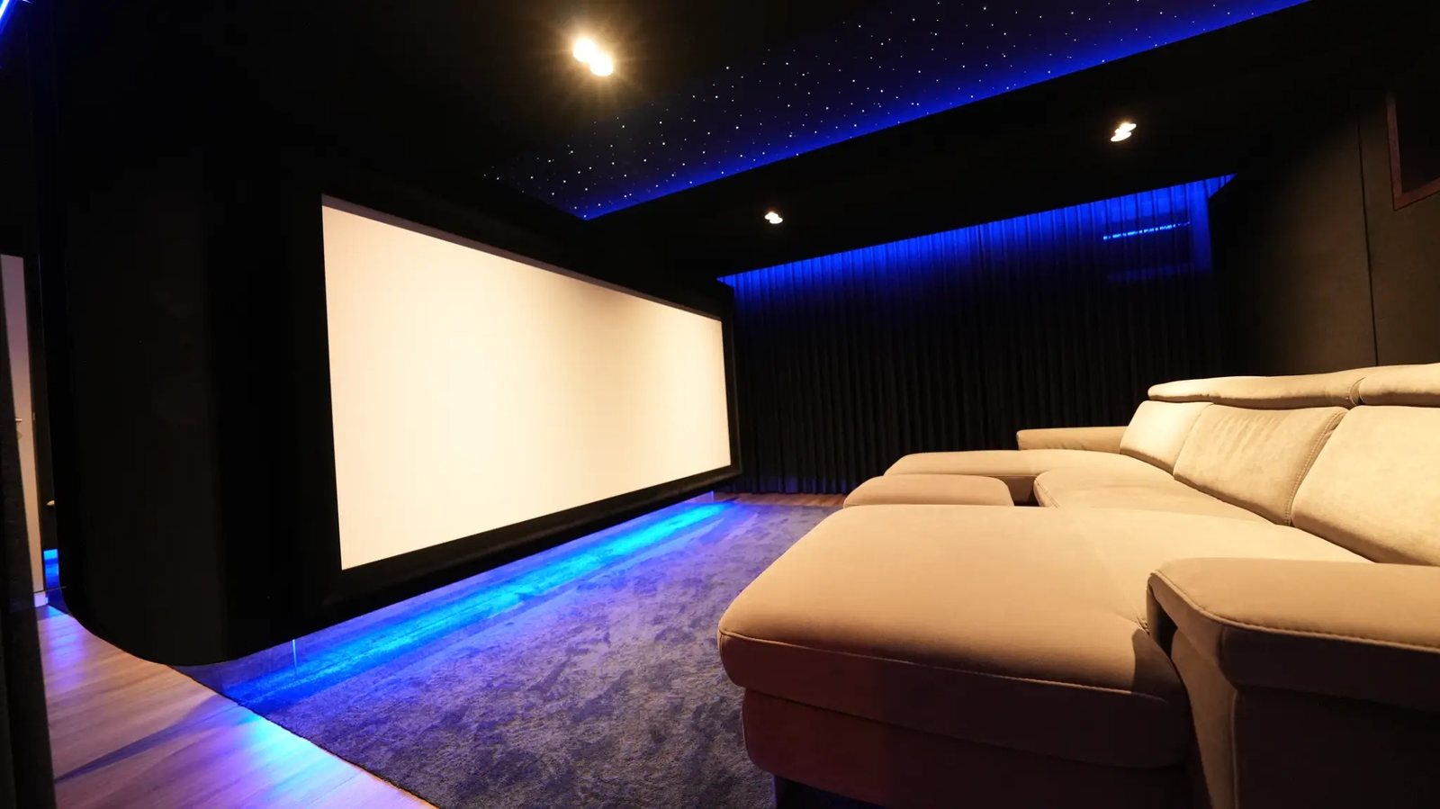 Leinwand in 300 Zentimeter Breite mit blauer Bodenlichtvoute und Couch im Vordergrund.
