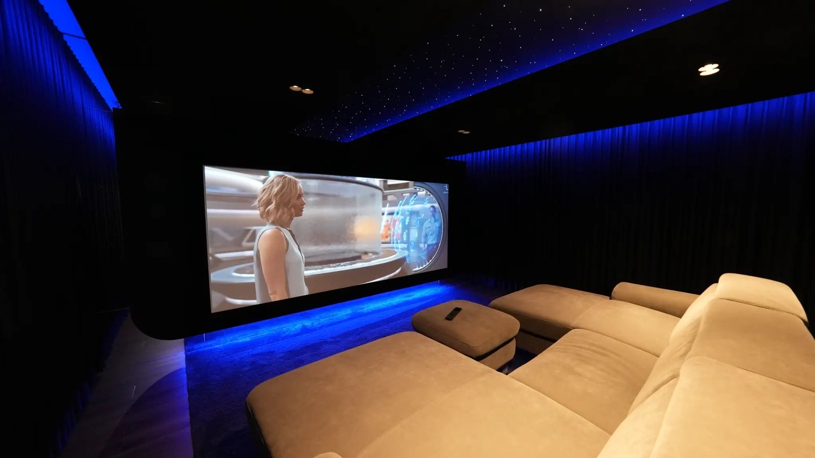 Film auf der Leinwand im Heimkino, davor die Couch und der Sternenhimmel an der Decke.